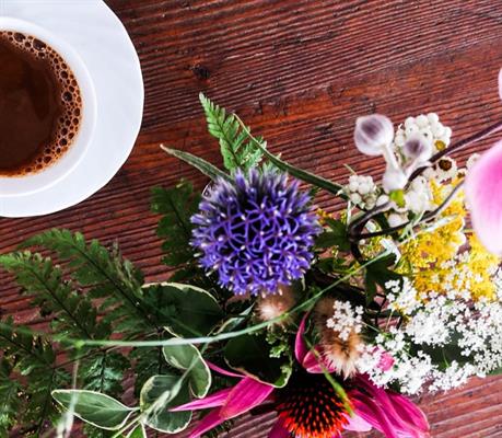 Eine Tasse Kaffee und ein Blumenstrauß auf einem Holztisch