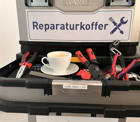 Werkzeugkoffer mit verschiedenen Werkzeugen und der Aufschrift "Reparaturkoffer"