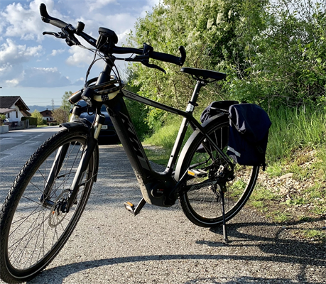Ein E-Bike mit Satteltaschen, im Hintergrund ein Auto und eine Wohnstraße
