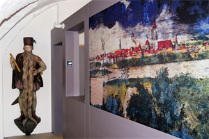 Eingangbereich des Bezirksmuseums Herzogsburg, rechts ein Gemälde von Braunau am Inn, links eine Figur von Hans Steininger